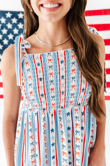 Woman wearing a bamboo-cotton maxi dress with a red, white, and blue pattern in front of an American flag.