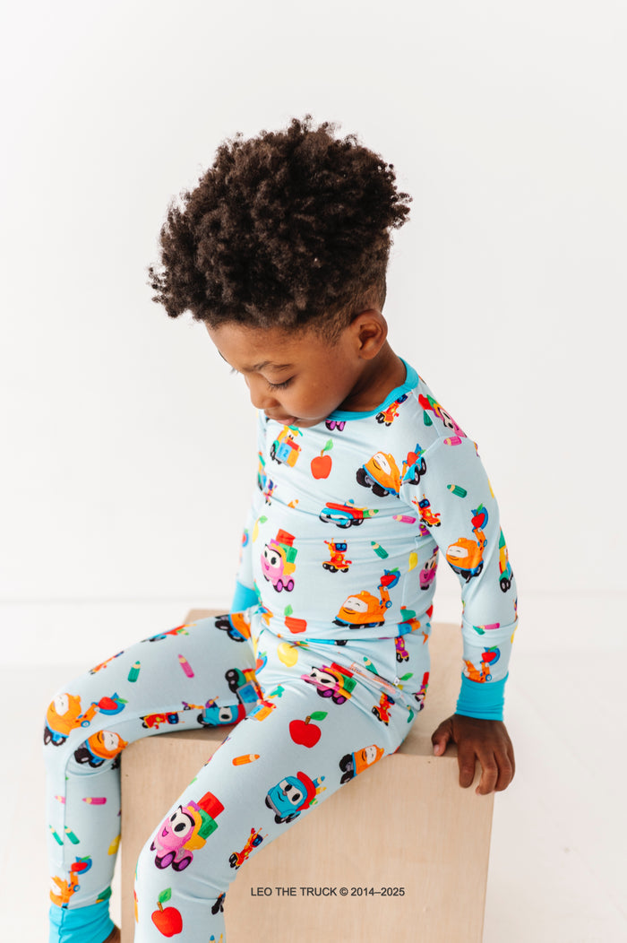 Little boy wearing blue Leo the Truck bamboo pajamas and sitting on a wooden block 