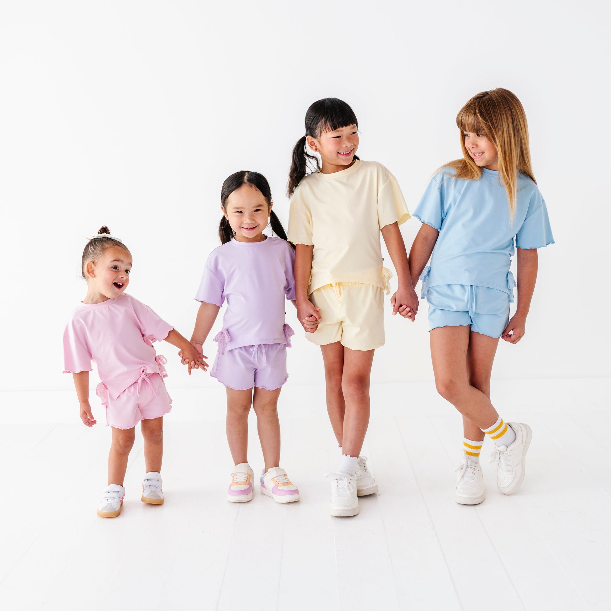 Four children holding hands and wearing matching outfits on a white background