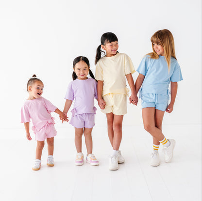 Four children holding hands and wearing matching outfits on a white background