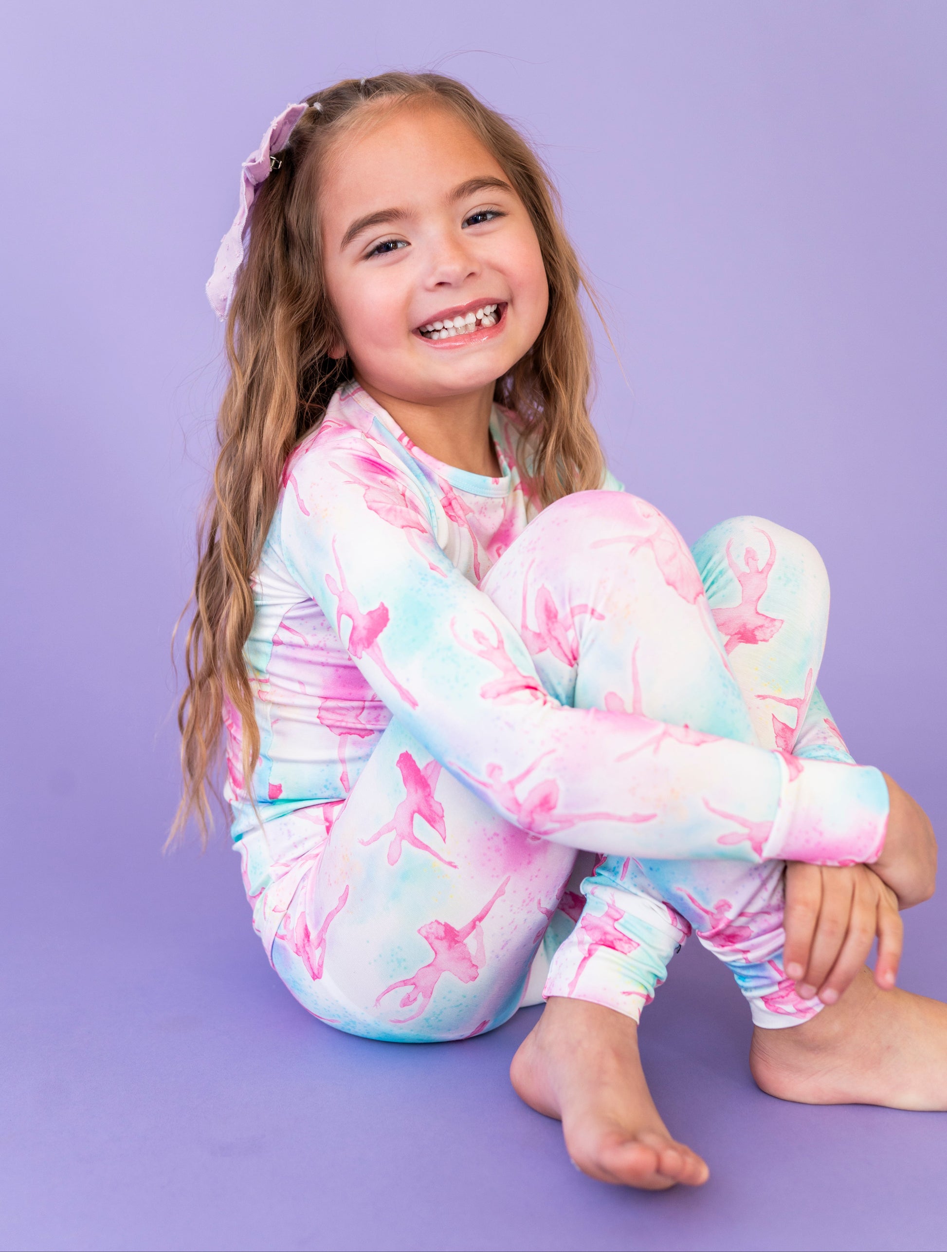Young girl wearing a colorful ballet-themed outfit on a purple background
