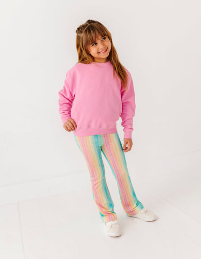 Young girl wearing a pink sweater and colorful pants on a white background