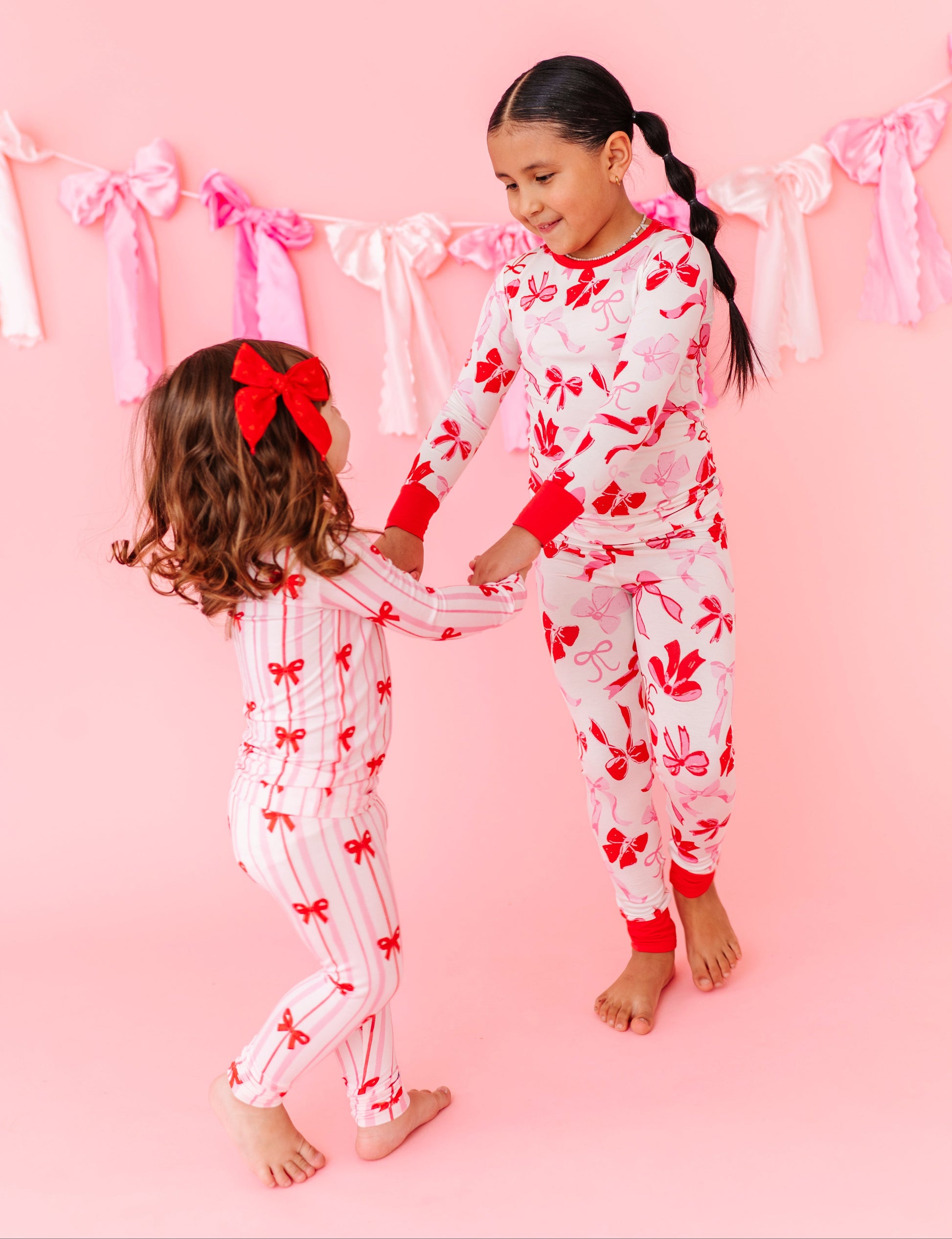 Girls wearing coordinating Birdie Bean bamboo pajamas with bow prints