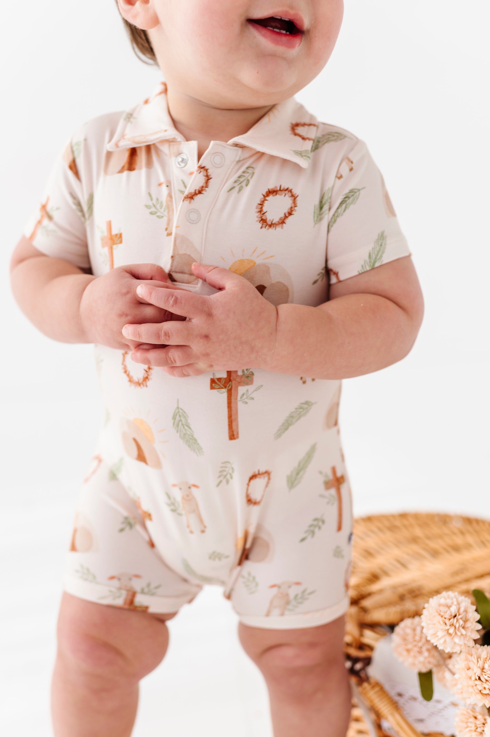Baby wearing a bamboo polo romper with Easter print on a white background
