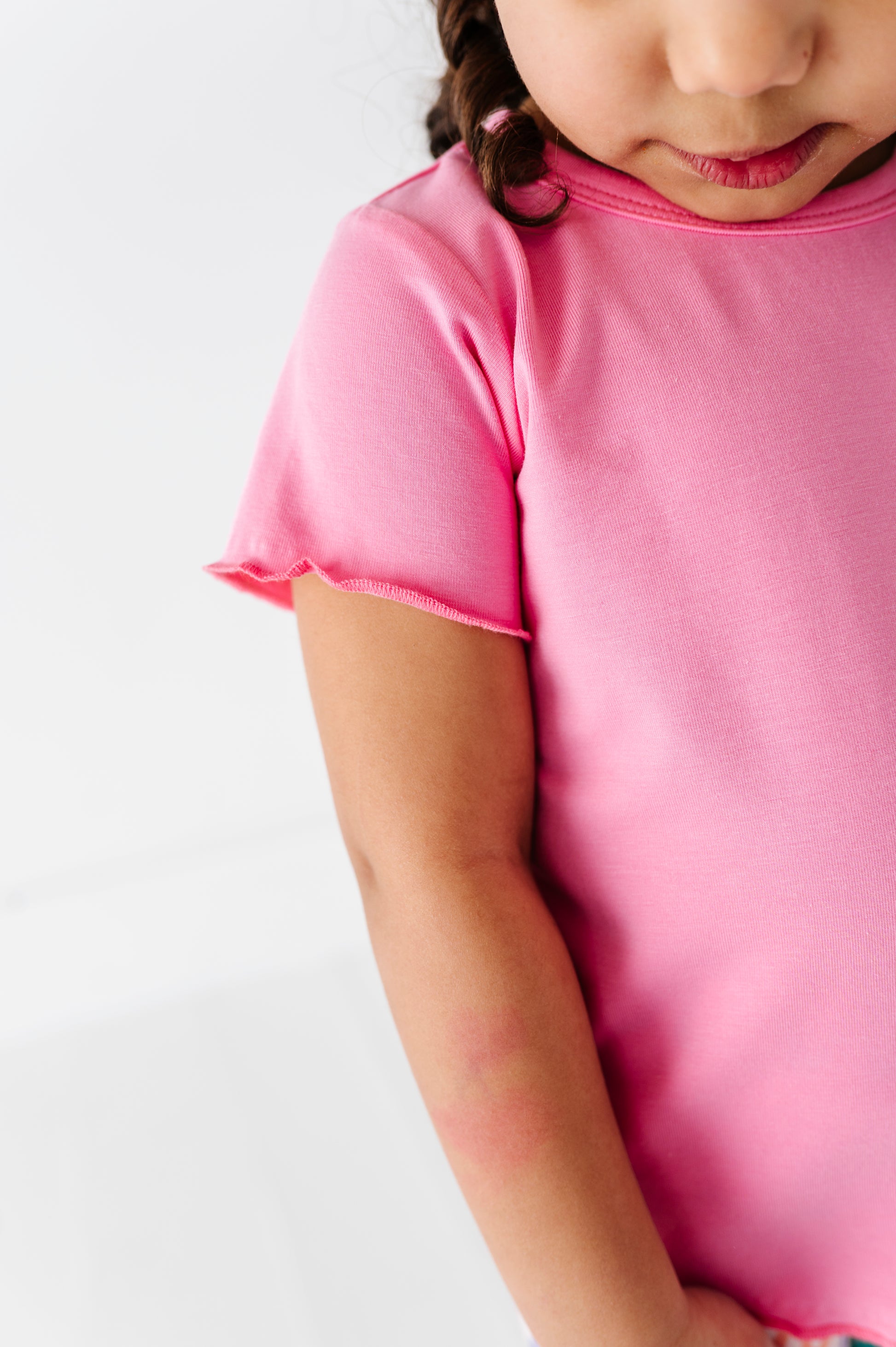 Child wearing a pink bamboo/cotton shirt on a white background