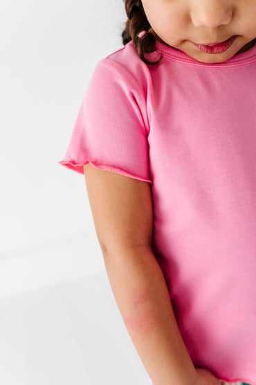 Child wearing a pink bamboo/cotton shirt on a white background