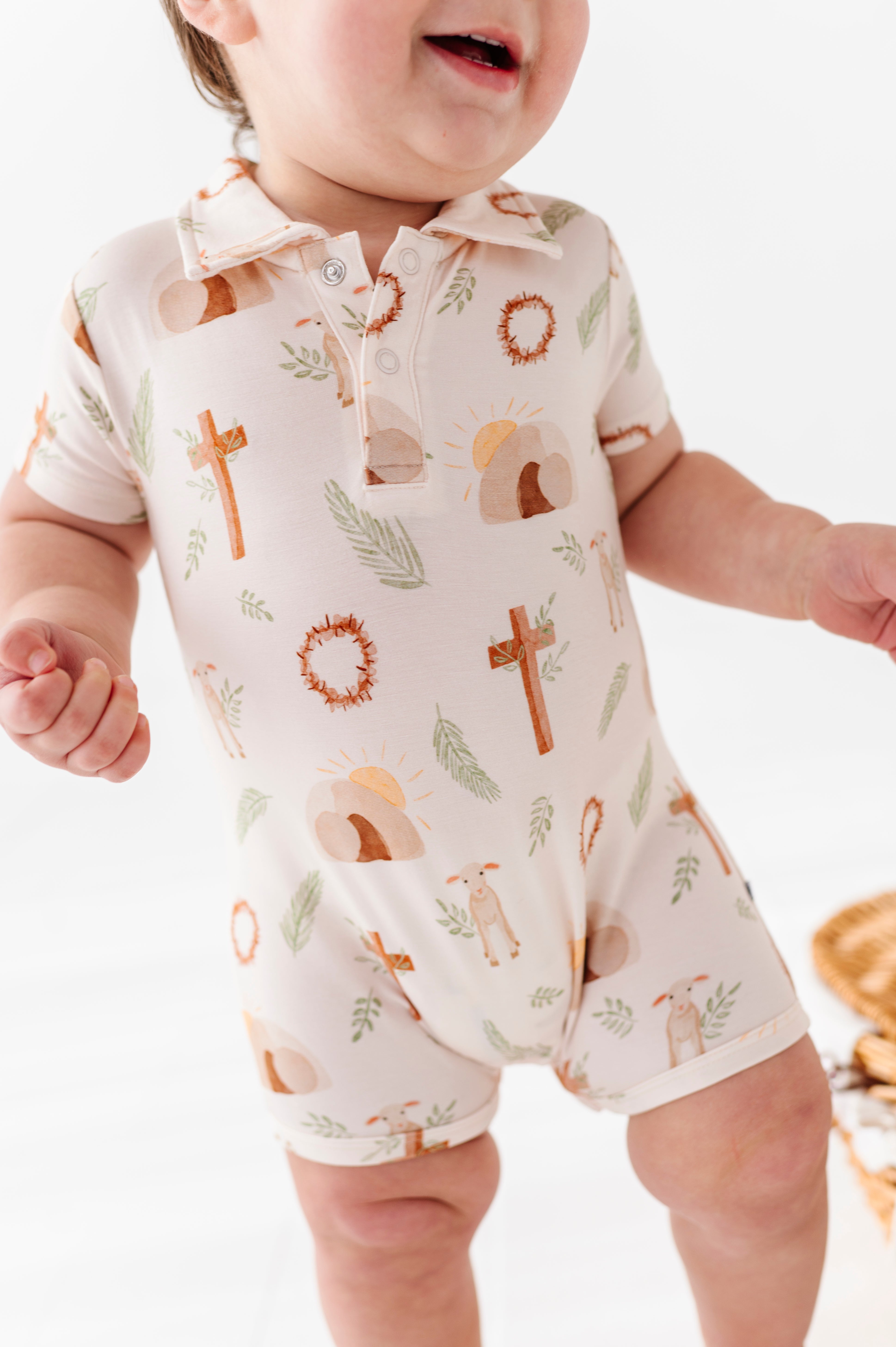 Baby wearing a bamboo polo romper with Easter-themed Christian print on a white background