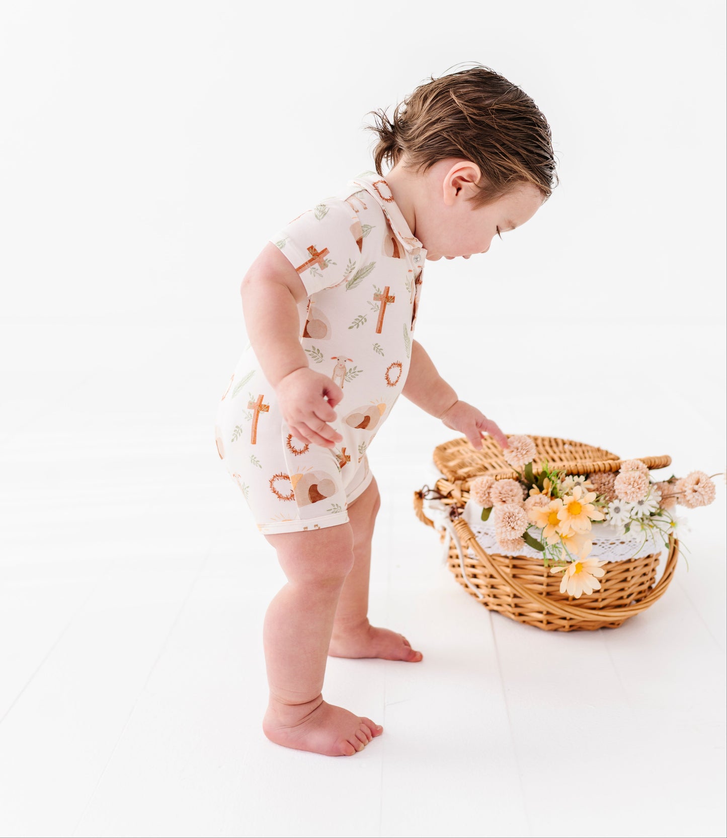 Child in an Easter themed bamboo outfit interacting with a basket of flowers on a white background