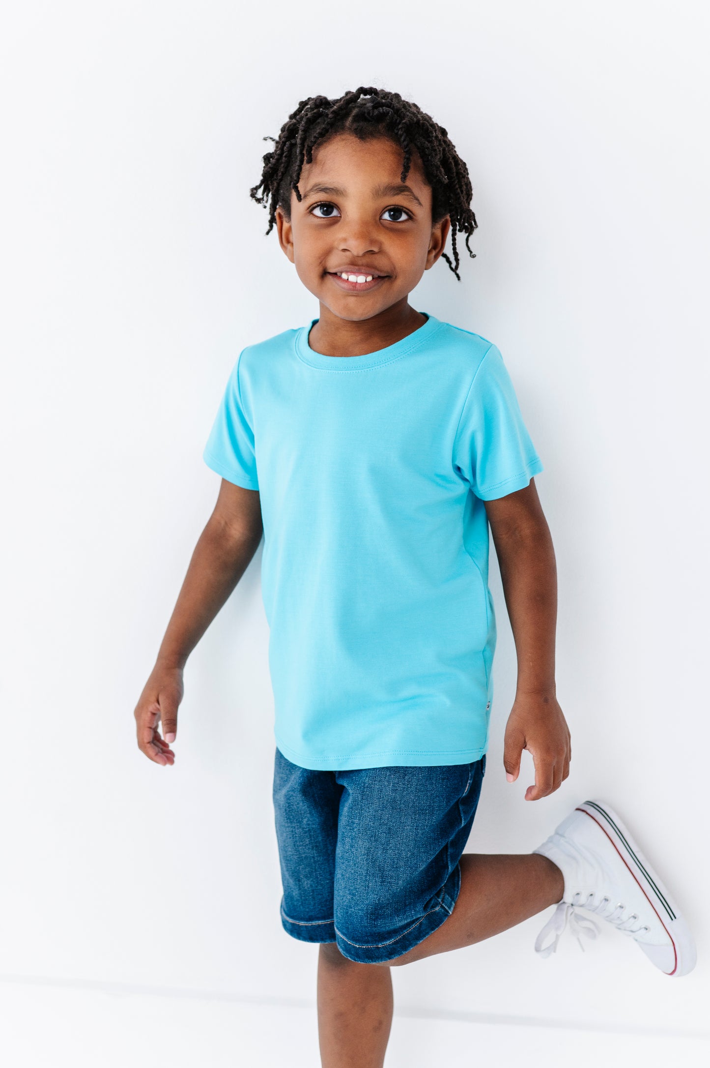 Child wearing a light blue bamboo blend t-shirt and denim shorts on a white background