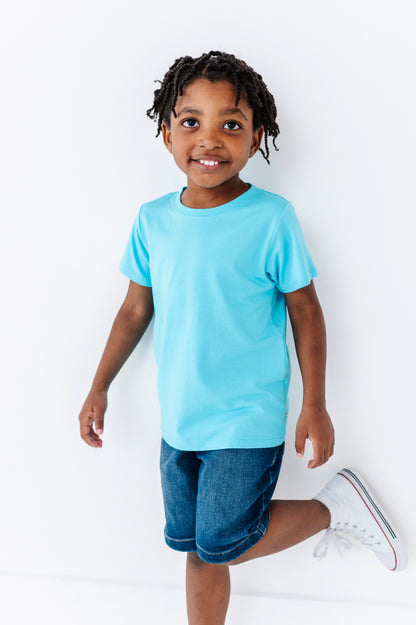 Child wearing a light blue bamboo blend t-shirt and denim shorts on a white background