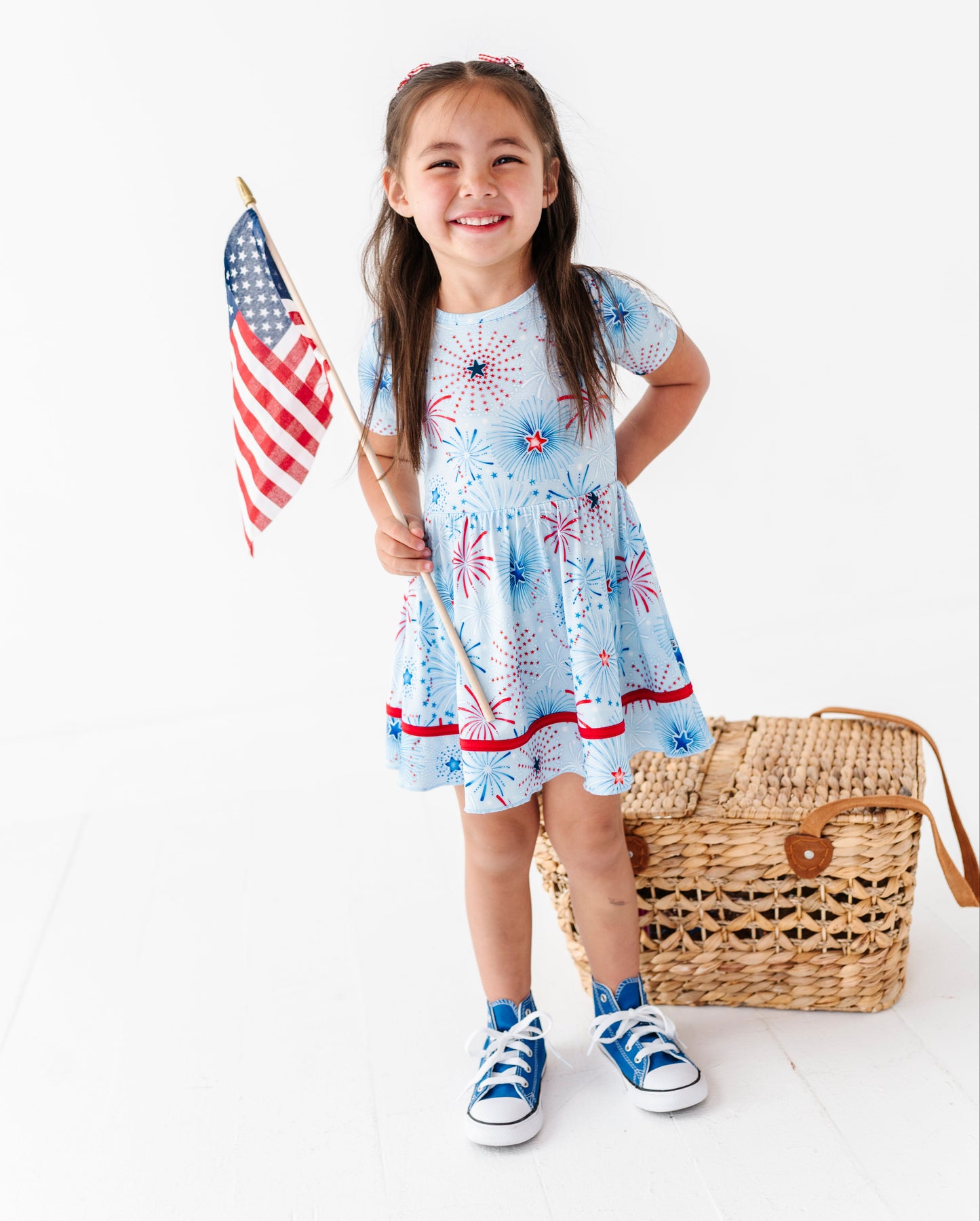 Young girl in a red, white, and blue bamboo, holding an American flag on a white background.