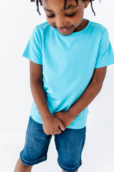 Child wearing a light blue bamboo blend t-shirt and denim shorts on a white background