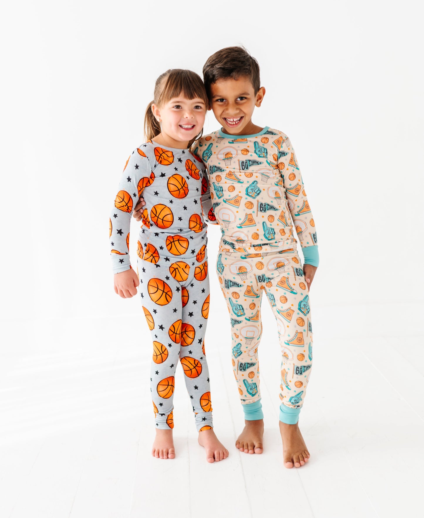 Two children wearing basketball themed pajamas on a white background