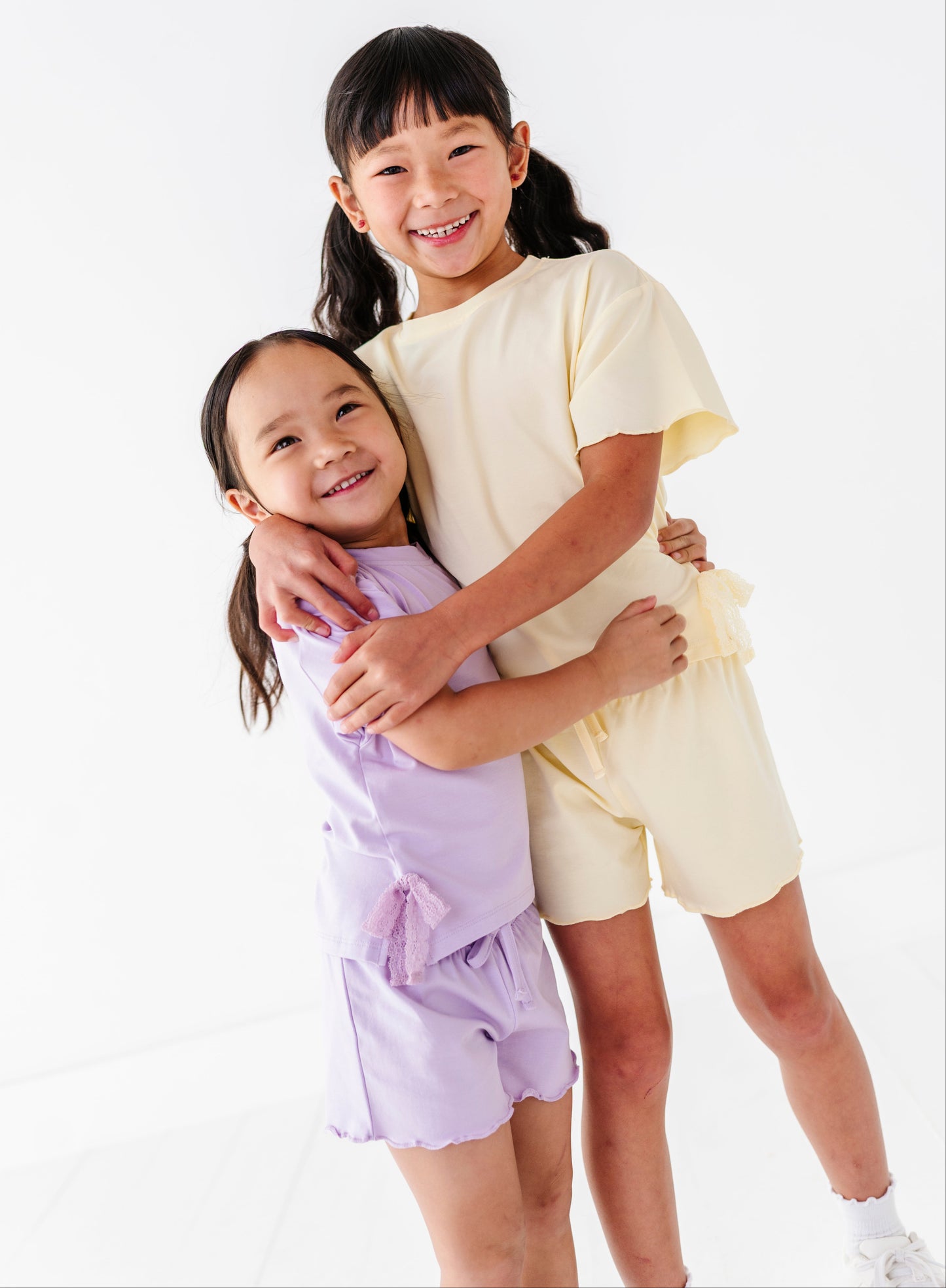 Two young girls hugging each other against a white background