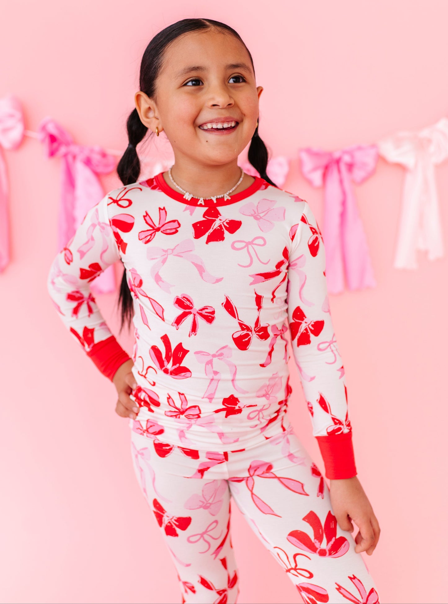 Child wearing Blushing Bows bamboo 2-piece pajamas with red and pink bow print
