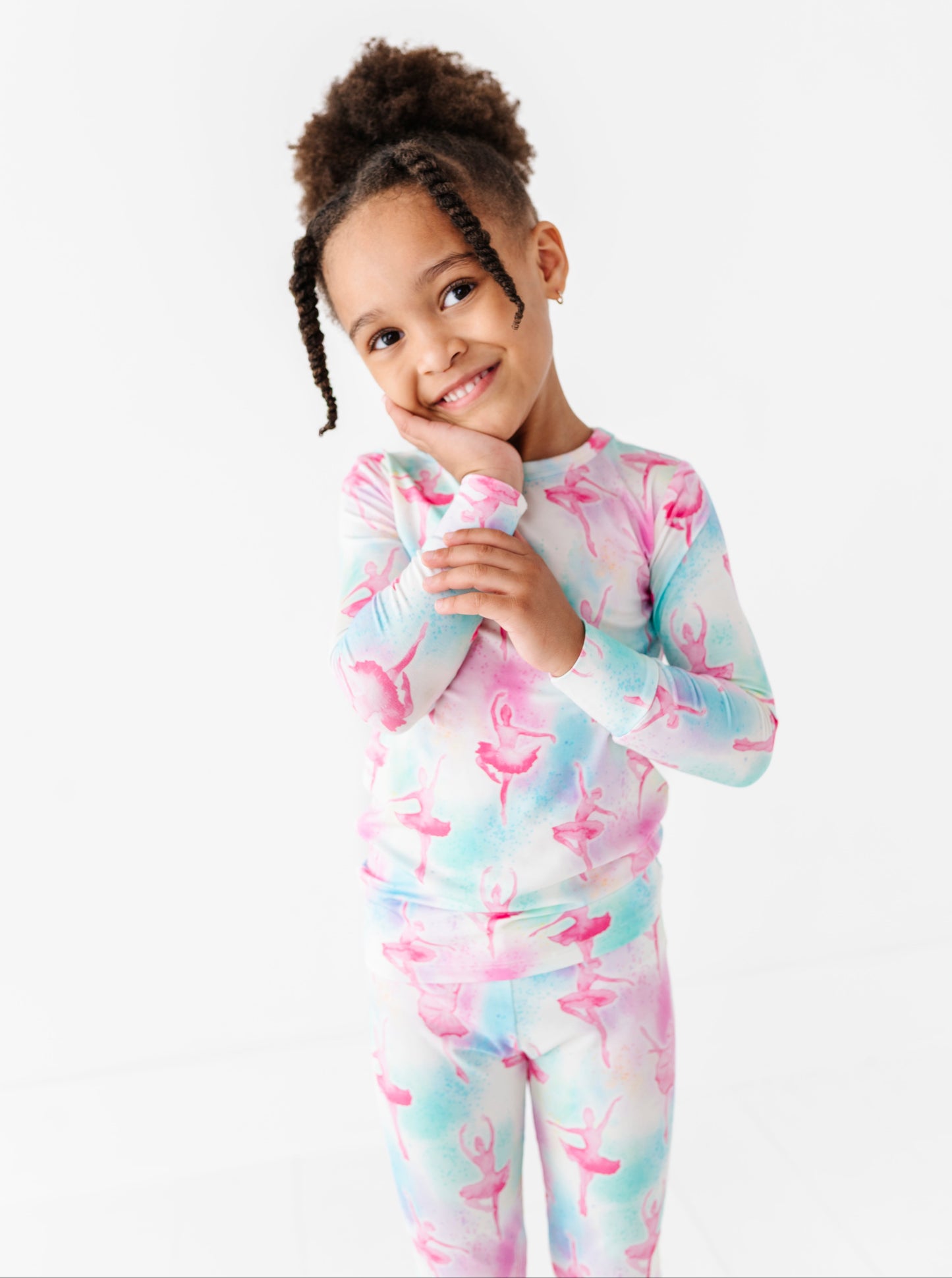 Young girl wearing a colorful ballet-themed onesie on a white background