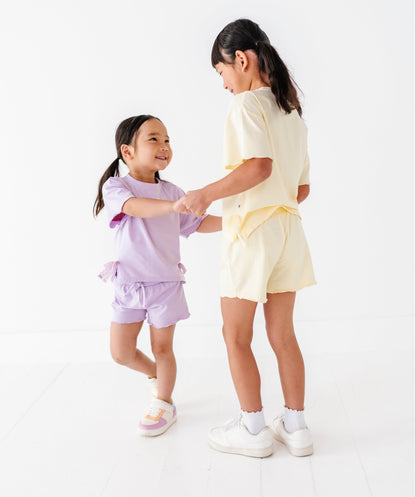 Two young girls in matching outfits standing on a white background