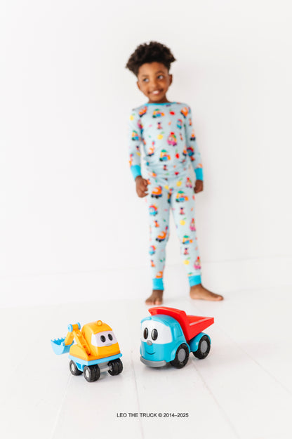 Child wearing colorful bamboo pajamas with two Leo the Truck toys on a white background