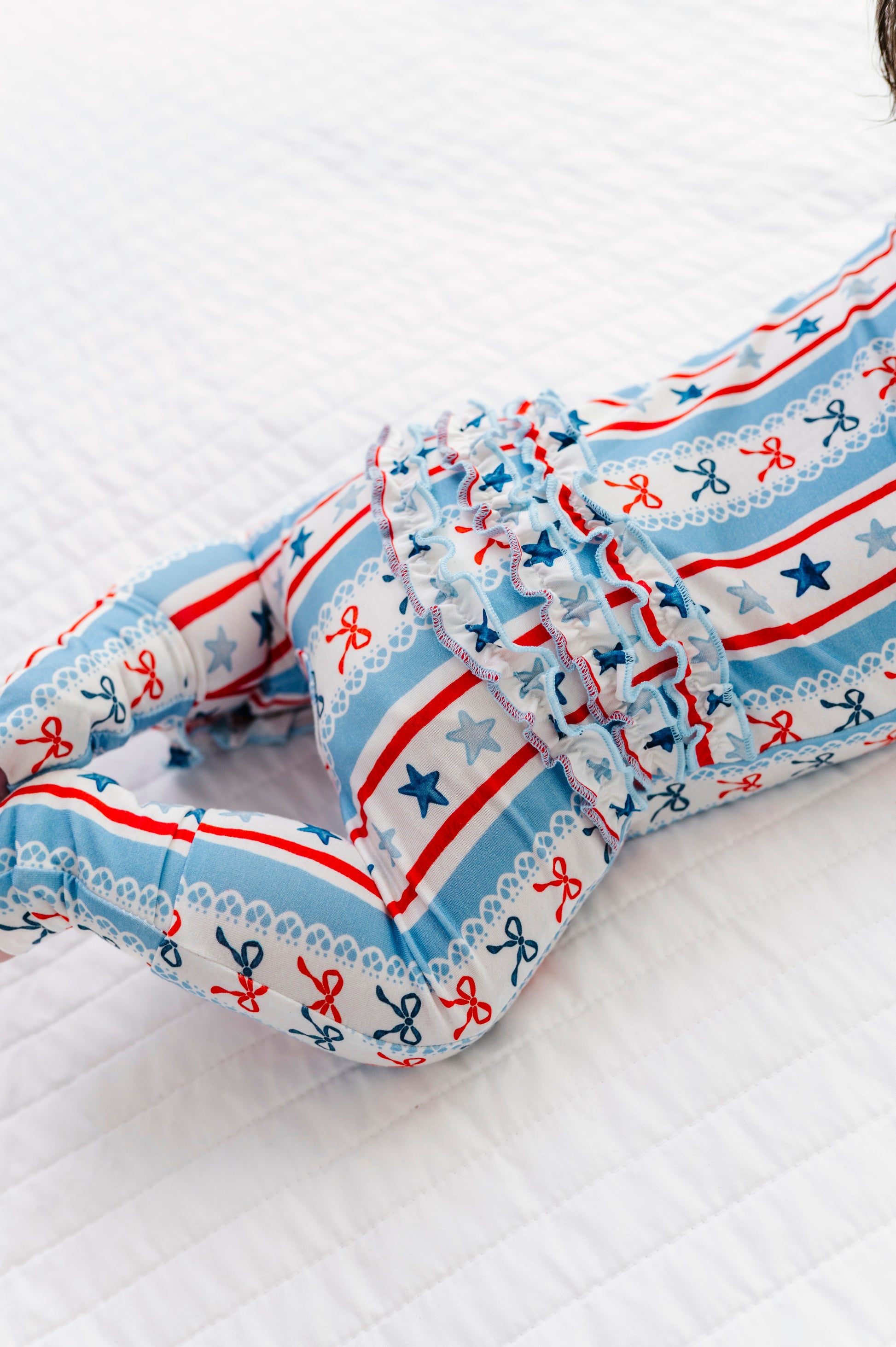 Baby wearing a bamboo convertible romper with red, white, and blue pattern on a white background