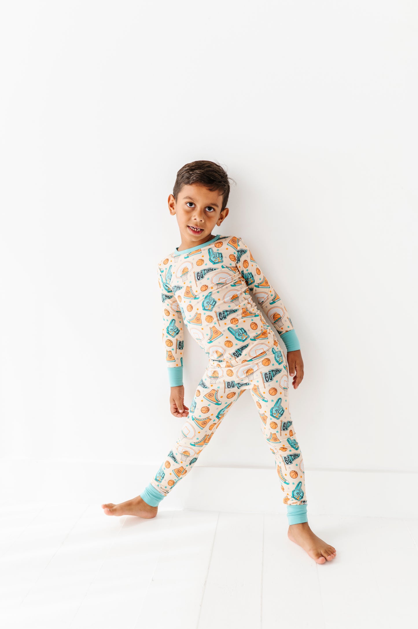 Child wearing a sports themed bamboo pj set on a white background