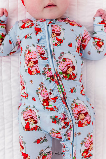 Baby wearing a bamboo zip romper with a Strawberry Shortcake™ pattern on a white background