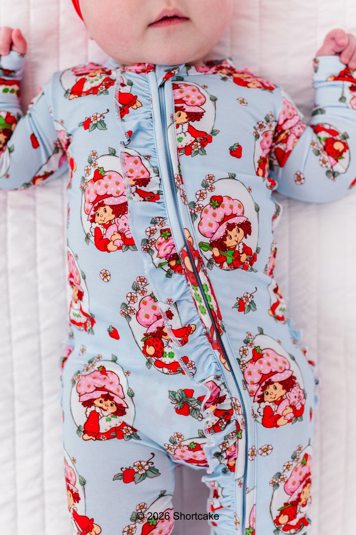 Baby wearing a bamboo zip romper with a Strawberry Shortcake™ pattern on a white background