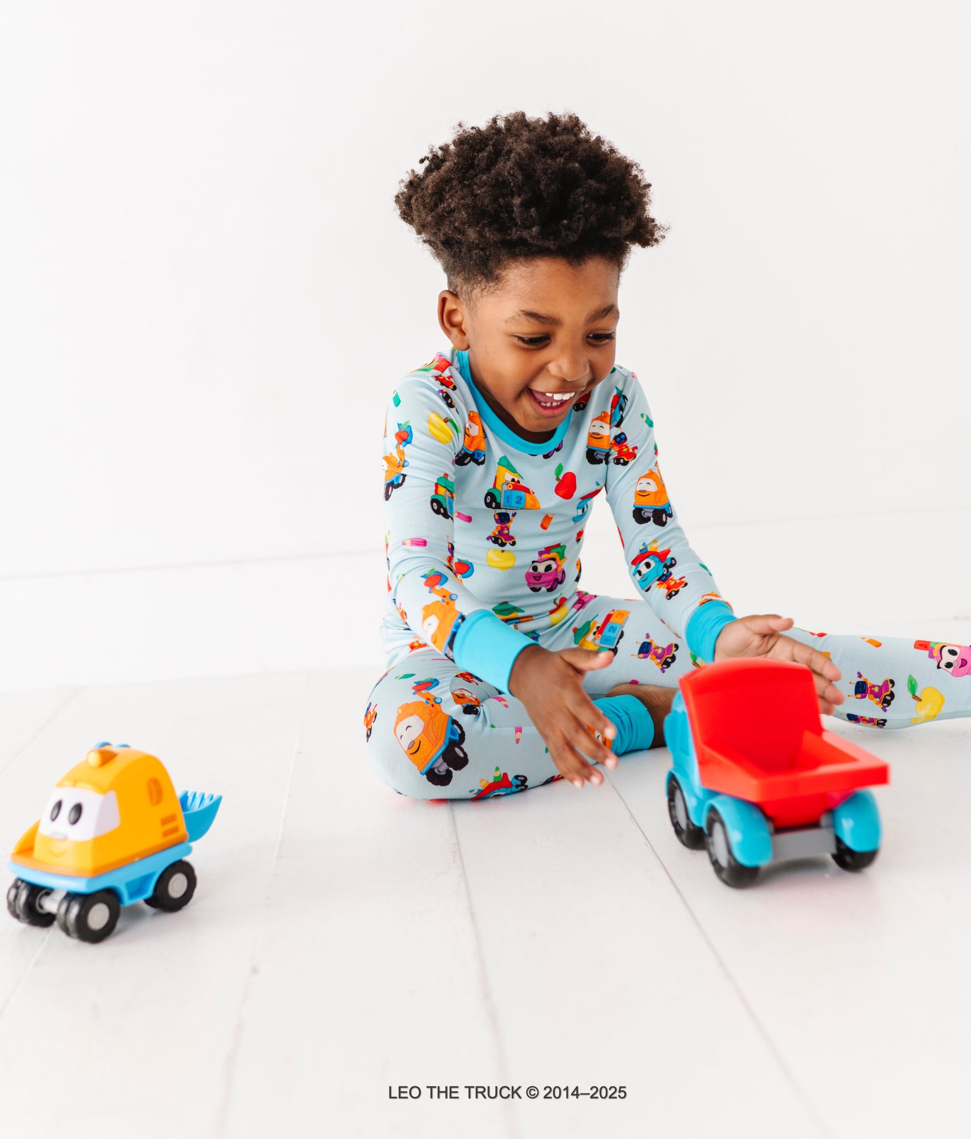 Toddler playing with Leo the Truck and crew toys while wearing bamboo Leo the Truck pajamas 