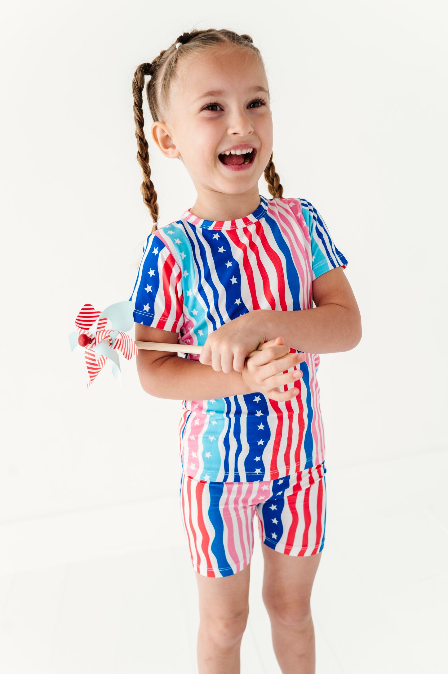 Child wearing a colorful American flag-themed bamboo pajama outfit holding a wooden toy.