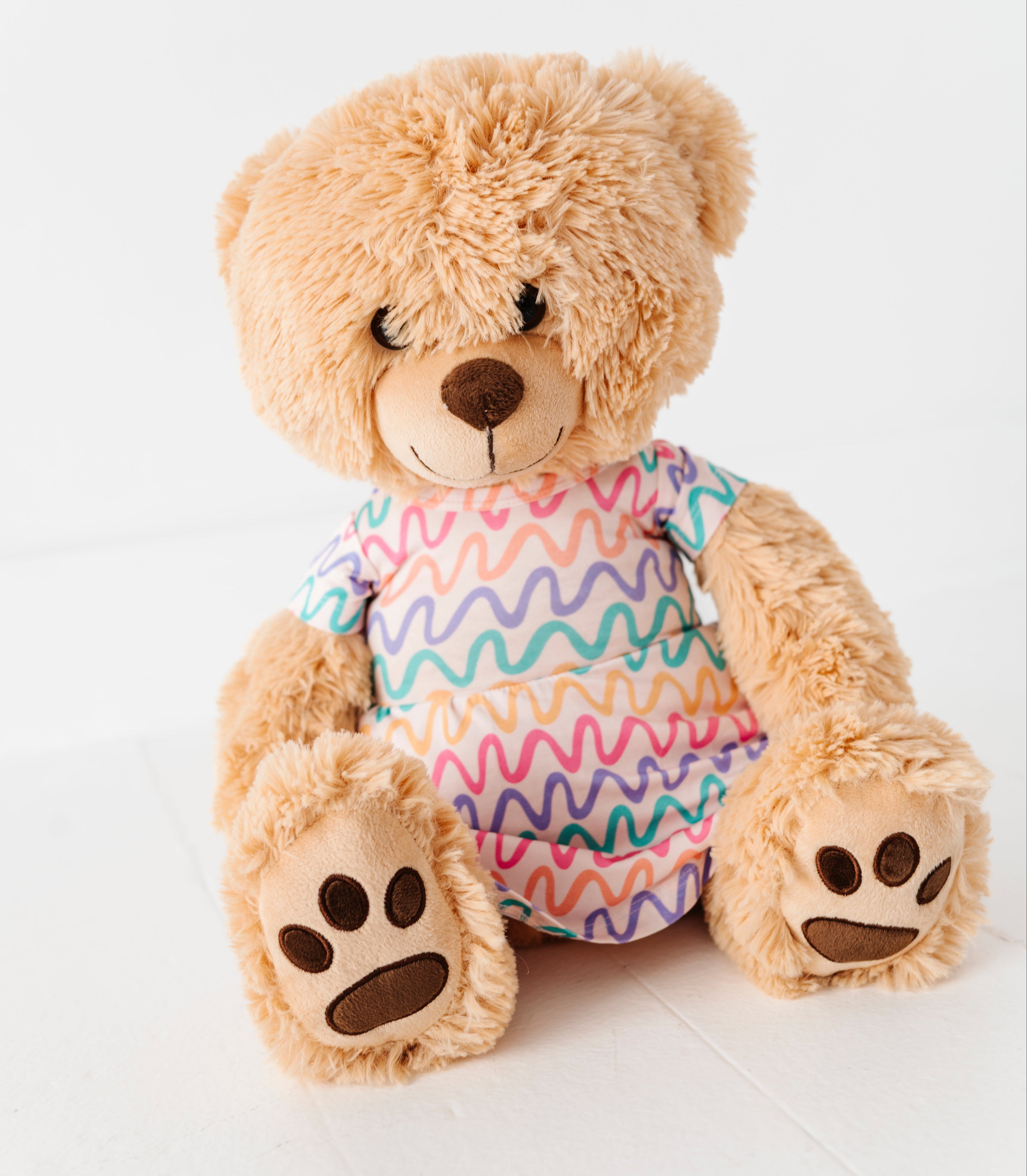Plush teddy bear wearing a colorful bamboo peplum shirt on a white background