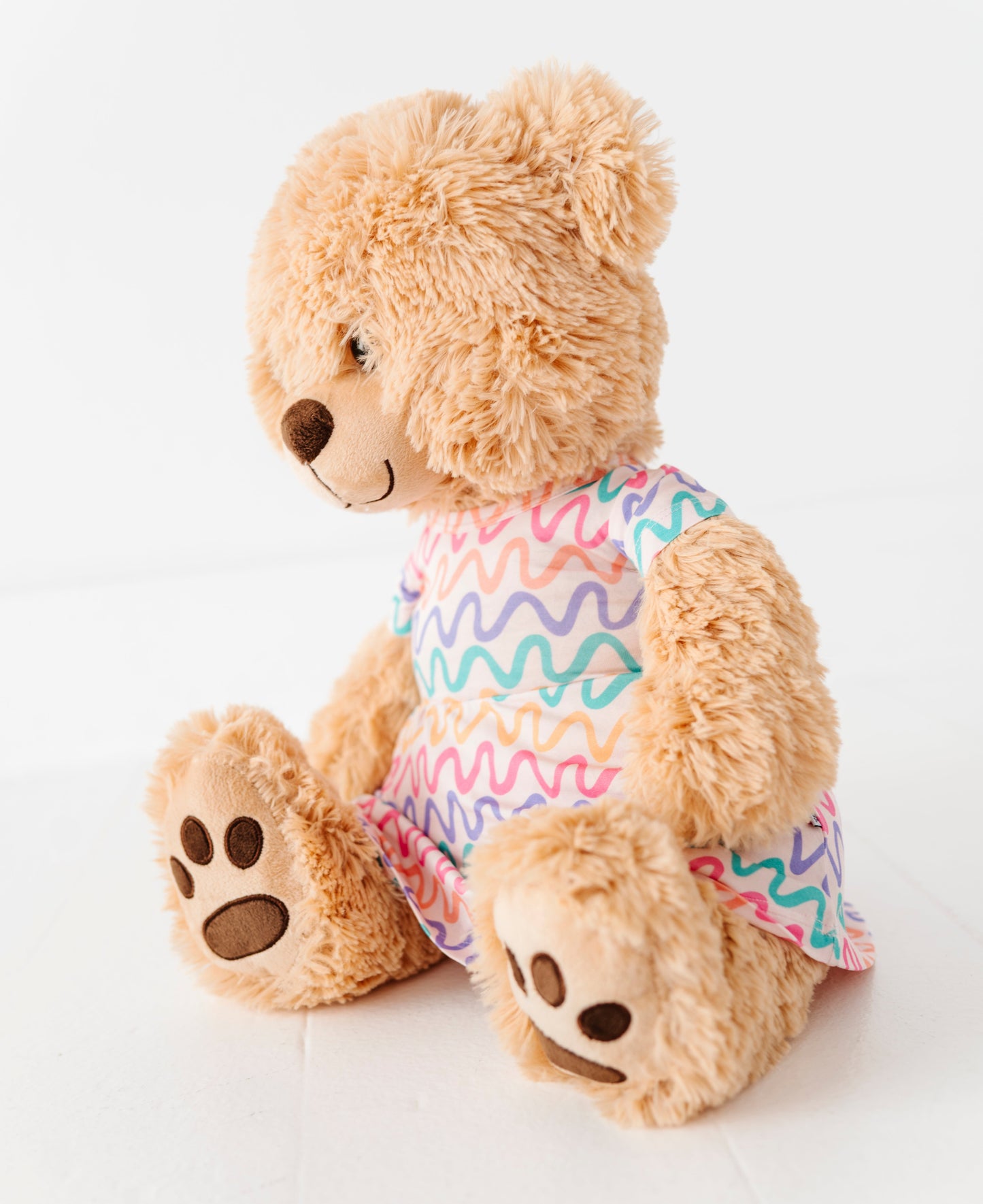 Plush teddy bear wearing a colorful bamboo peplum top on a white background