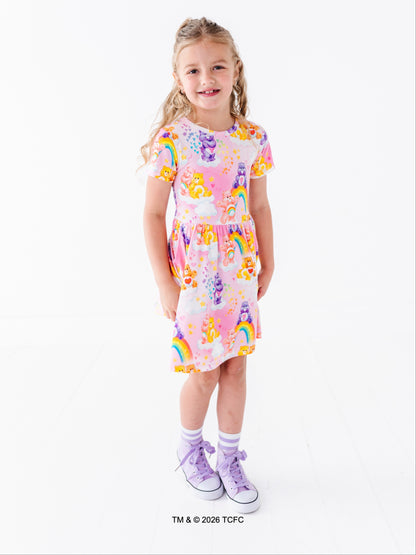 Young girl wearing a colorful bamboo dress with Care Bears™ design on a white background.
