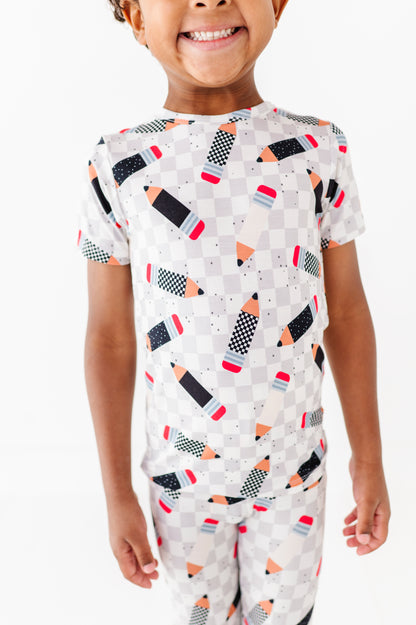 Child wearing a pajama set with pencil pattern on a white background