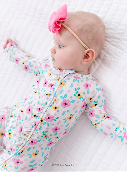 Baby in a floral PEEPS® onesie lying on a white quilted surface