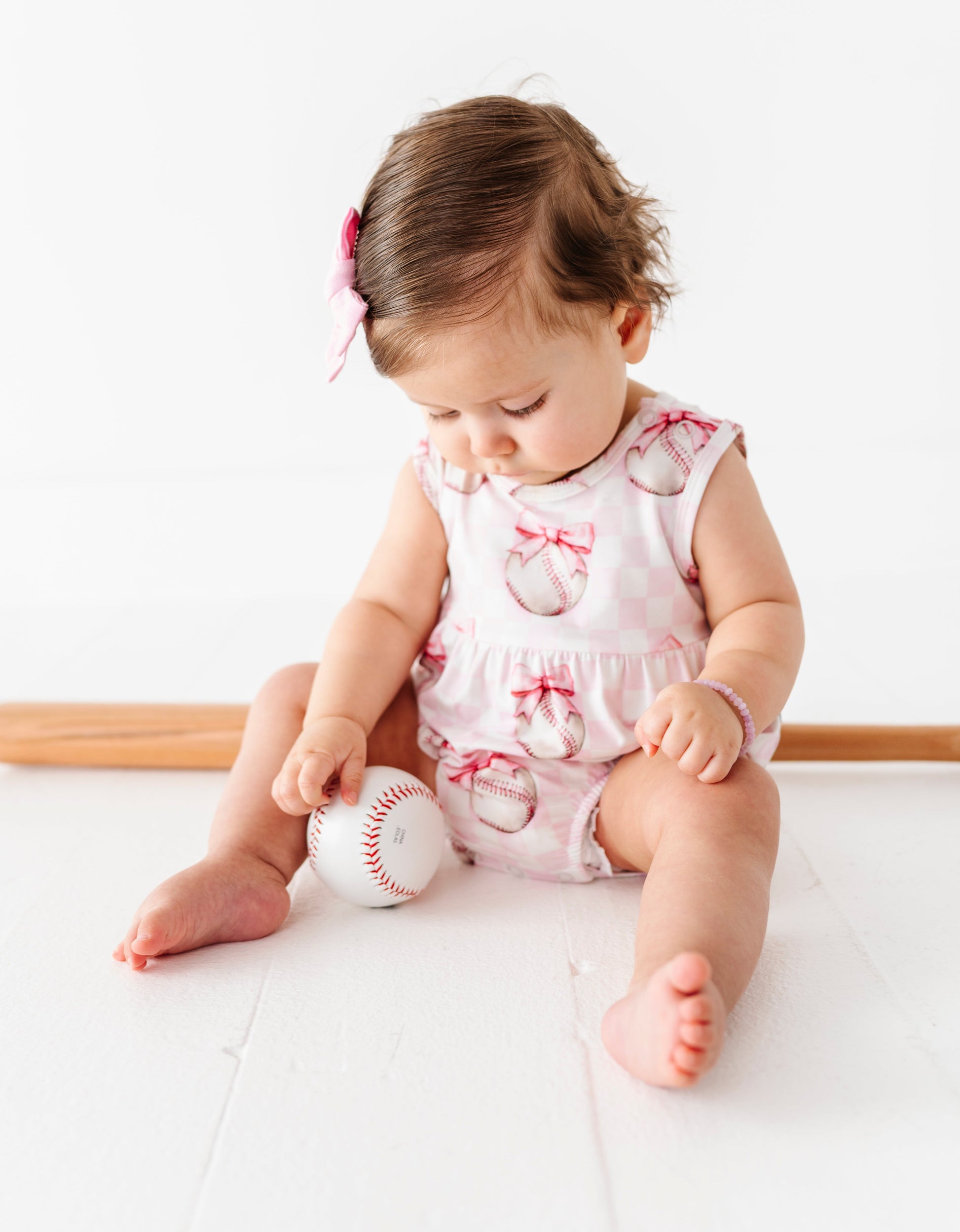 Child playing with a baseball on a white surface