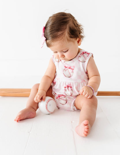 Child playing with a baseball on a white surface