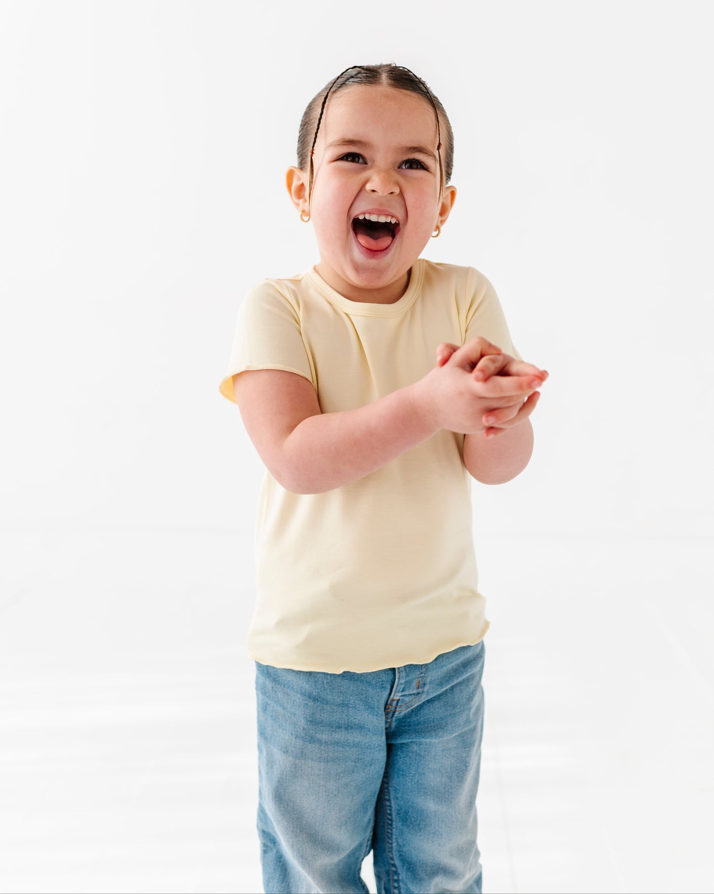 Child wearing a yellow shirt and blue jeans on a white background