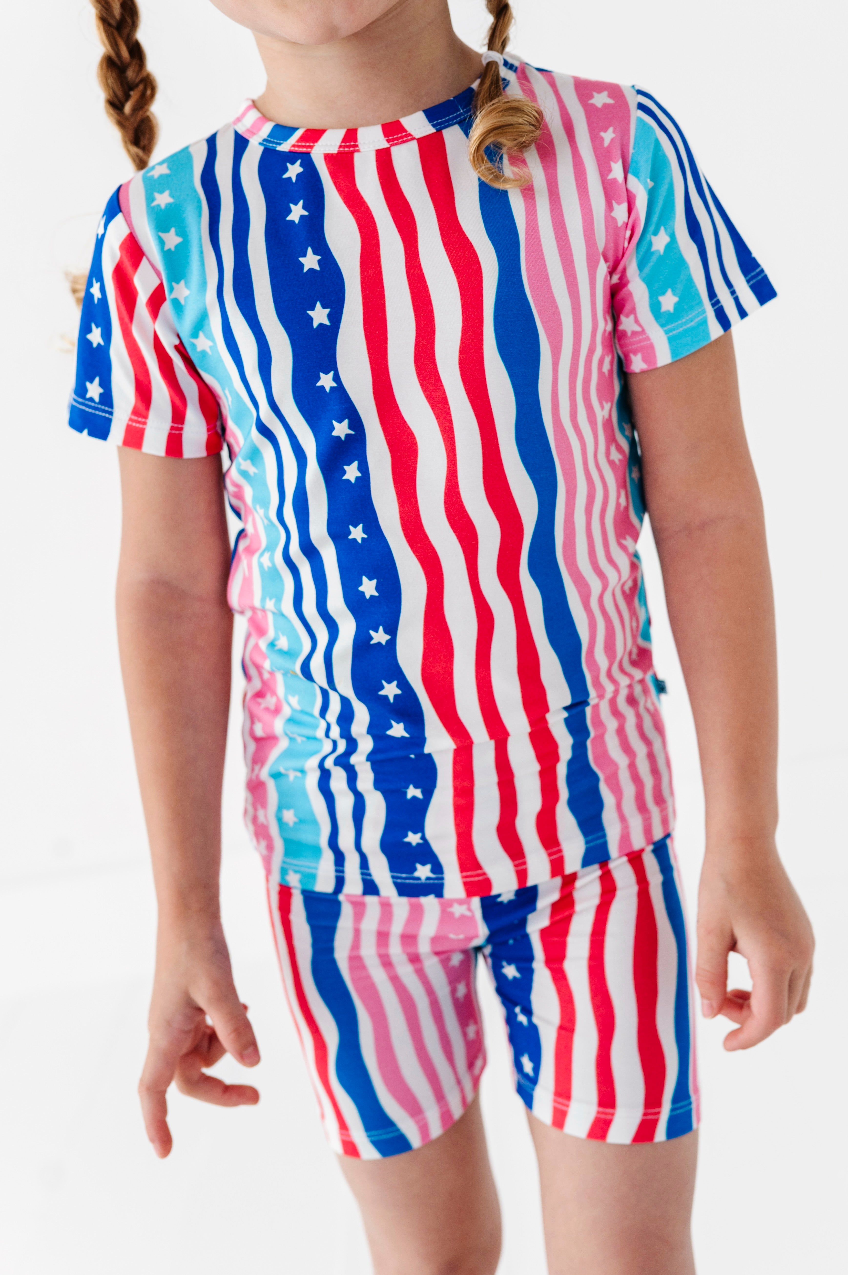 Child wearing a red, white, and blue striped bamboo pajama outfit with star patterns on a plain background