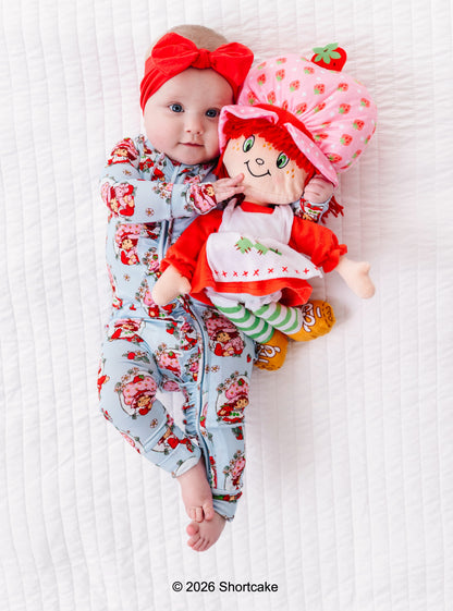 Baby in Strawberry Shortcake™ bamboo pajamas with a matching Strawberry Shortcake™ doll on a white background