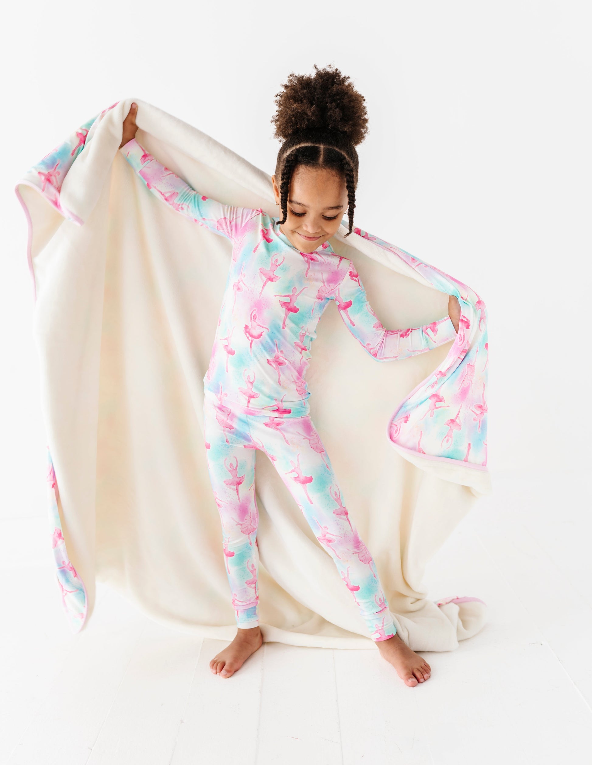 Child wearing watercolor bamboo pajamas holding a matching bamboo plush blanket on a white background