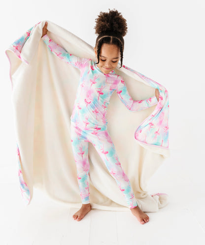 Child wearing a colorful pajama set holding a matching blanket on a white background