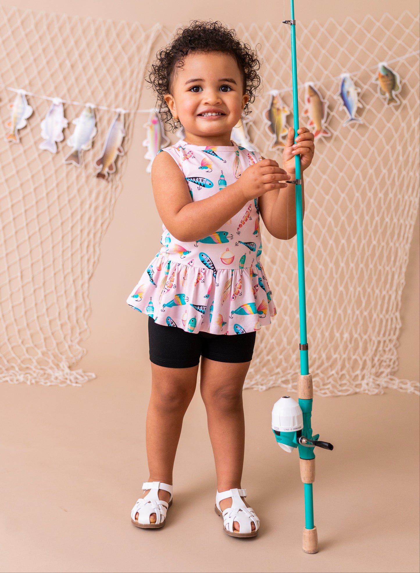 Child holding a fishing rod with a decorative net and fish banner in the background