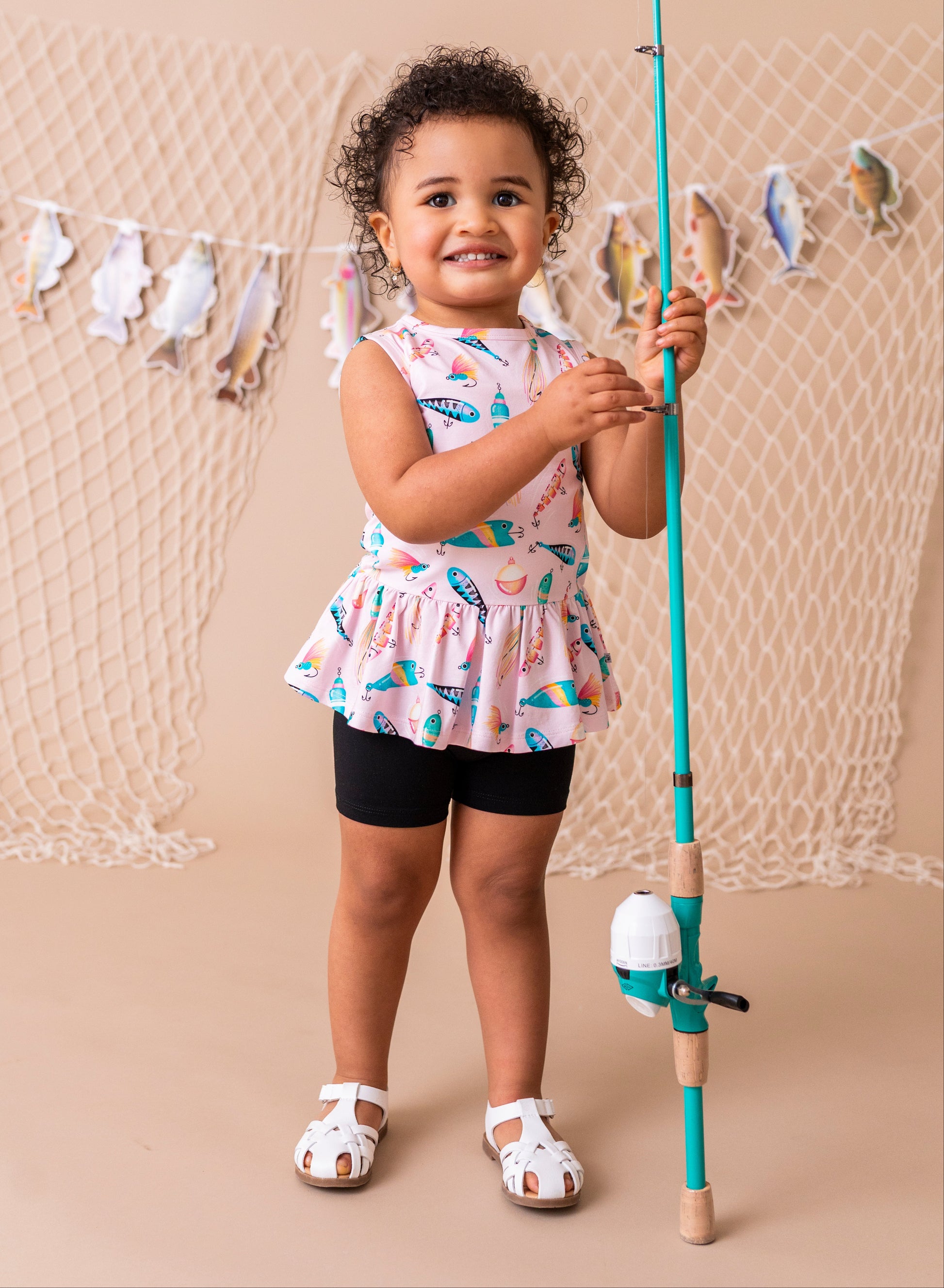 Child holding a fishing rod with a decorative net and fish banner in the background