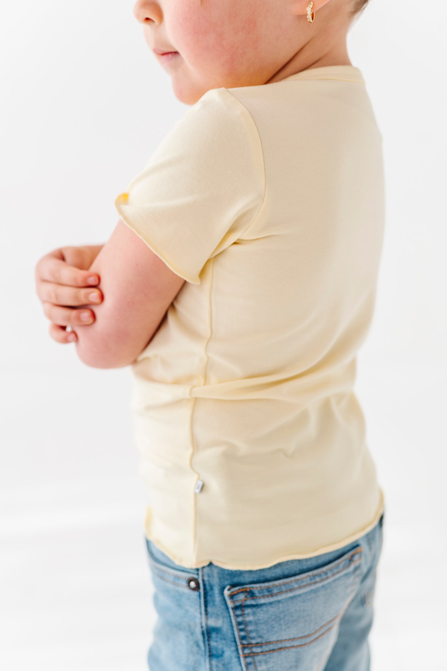 Child wearing a light yellow bamboo t-shirt and blue jeans on a white background