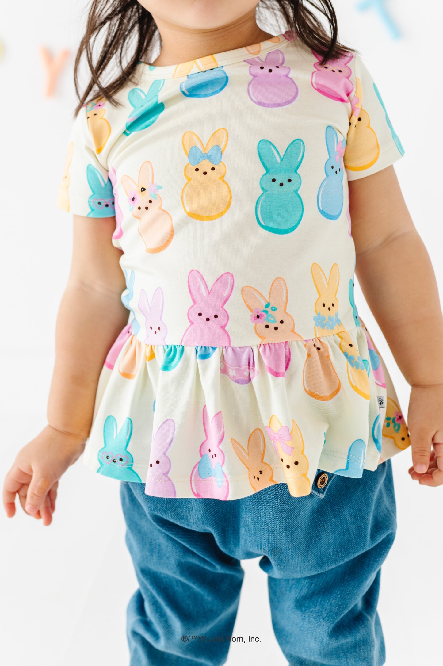 Child wearing a colorful Peeps-themed top with bunny designs on a white background