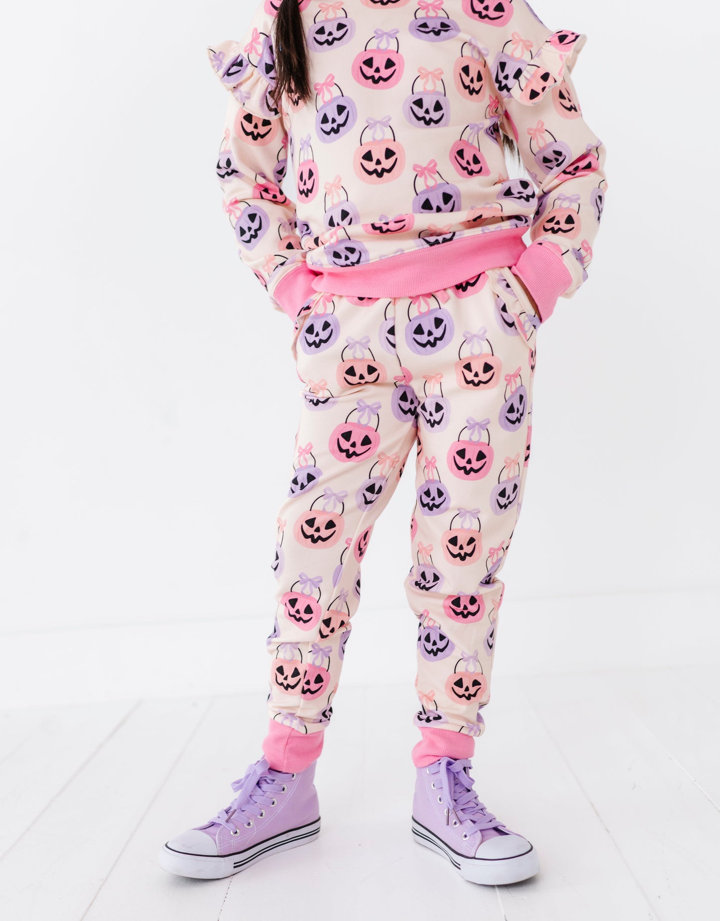 Girl wearing a bamboo jogger set with pumpkin pattern on a white background