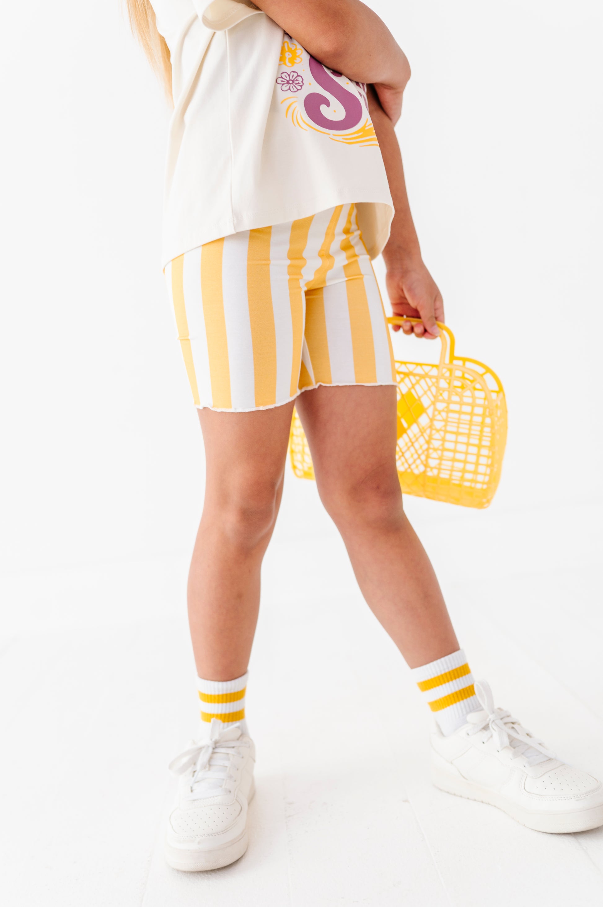 Girl  wearing a white outfit with yellow accents, holding a yellow basket, on a white background
