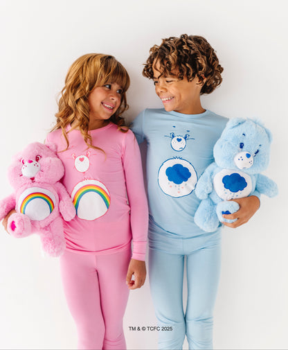 Kid smiling in pink Care Bears Cheer Bear pajamas on white background