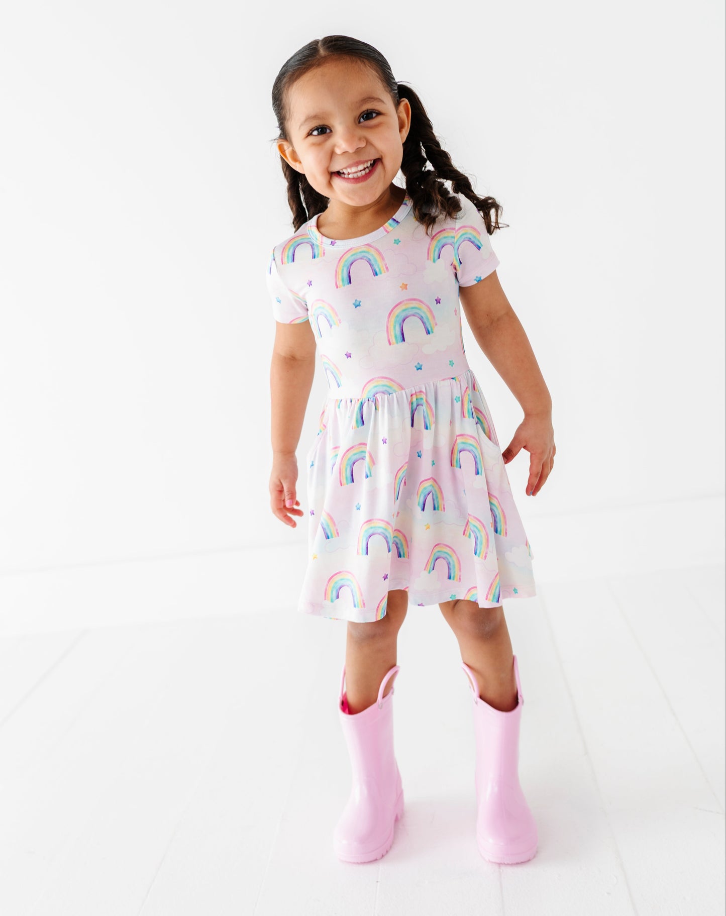 Young girl wearing a bamboo dress with watercolor rainbow patterns on a white background