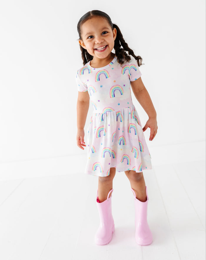 Young girl wearing a bamboo dress with watercolor rainbow patterns on a white background