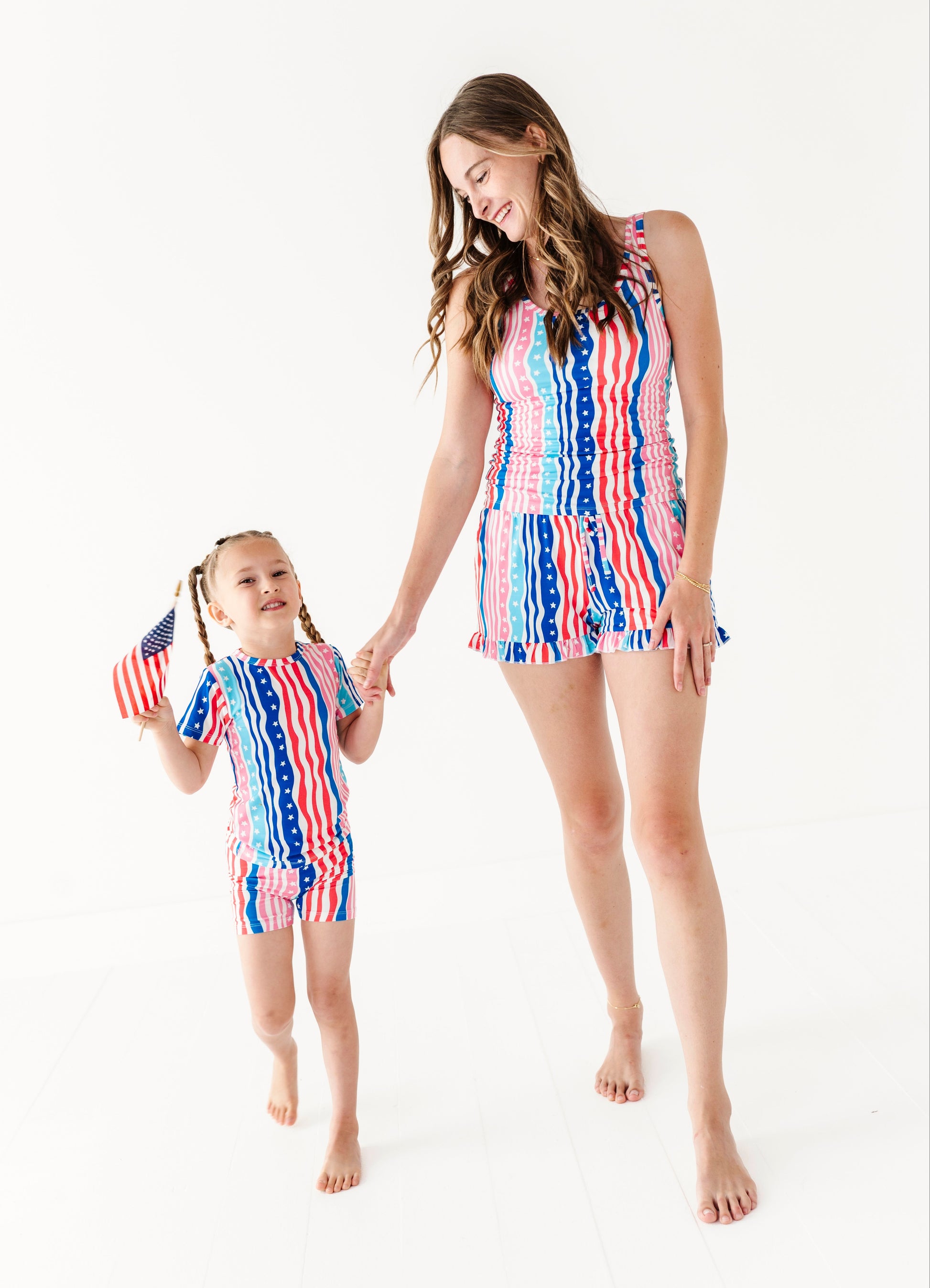 Mom and daughter wearing matching red, white, and blue bamboo pajama shorts on a white background